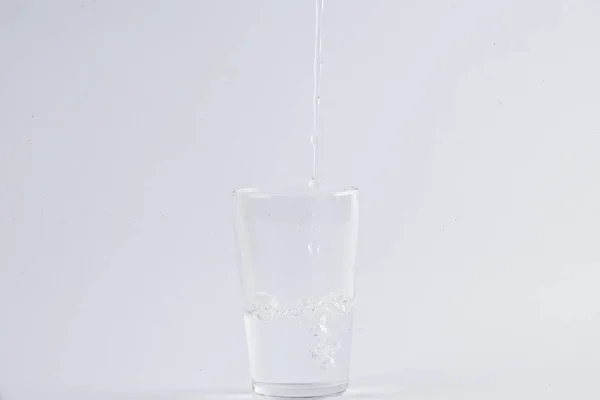 白い背景を透明なガラスに注ぐ水 — ストック写真