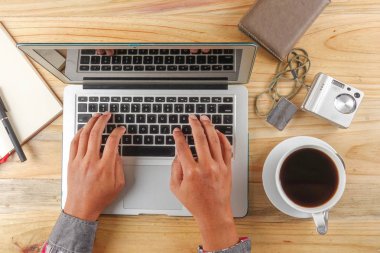 Vintage hipster ahşap masaüstü üstten görünüm, erkek eller bir dizüstü bilgisayar kullanarak.