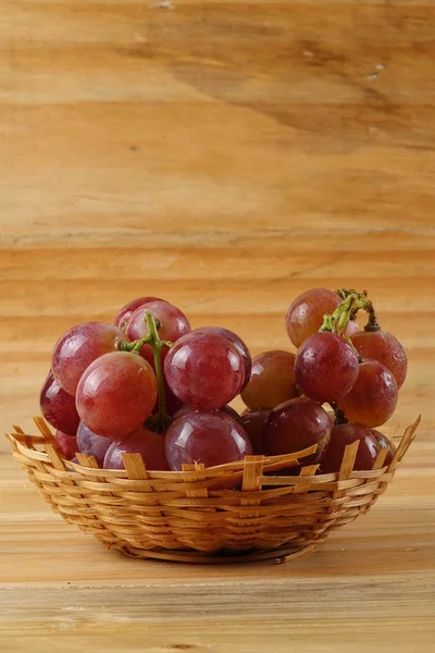 Червоний виноград на кошику над дерев'яним тлом . — стокове фото