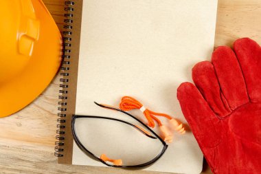 Emanet şapka, eldiven, gözlük, kulak tıkacı ve not defteri. Sağlığı ve güvenliği kavramı.