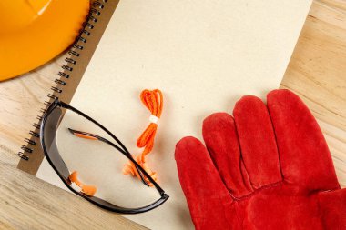 Emanet şapka, eldiven, gözlük, kulak tıkacı ve not defteri. Sağlığı ve güvenliği kavramı.