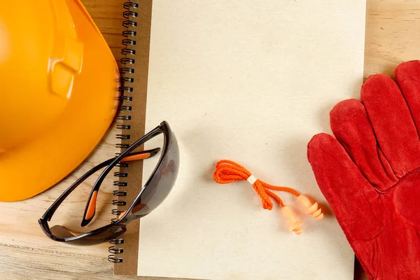 Chapéu de segurança, luva, óculos, tampões de ouvido e caderno de notas. Conceito de saúde e segurança . — Fotografia de Stock