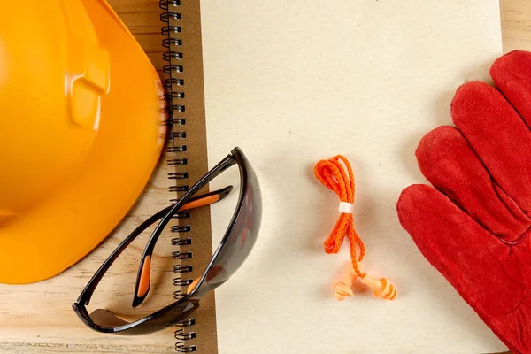 Emanet şapka, eldiven, gözlük, kulak tıkacı ve not defteri. Sağlığı ve güvenliği kavramı.