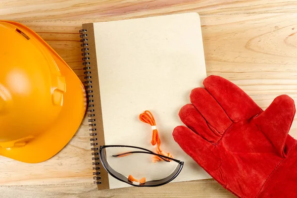 Emanet şapka, eldiven, gözlük, kulak tıkacı ve not defteri. Sağlığı ve güvenliği kavramı.