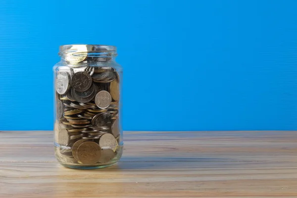 Vasetto massone con monete sopra sfondo blu goccia. Concetto di risparmio . — Foto Stock
