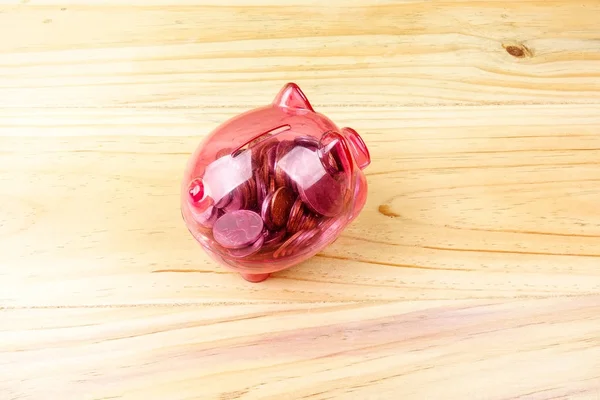 Red piggy bank and jar of coins on the wooden table. Saving and investment concept.