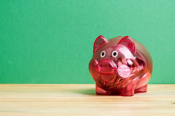 Red piggy bank and jar of coins on green background. Saving and investment concept.
