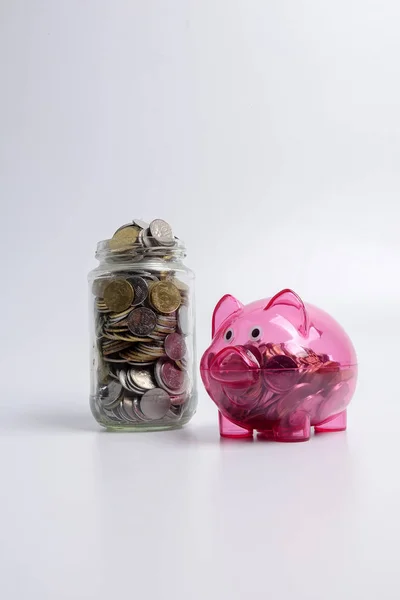 Red piggy bank and jar of coins on white background. Saving and investment concept.