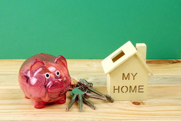 Piggy bank, small house and a bundle of house key. House saving concept