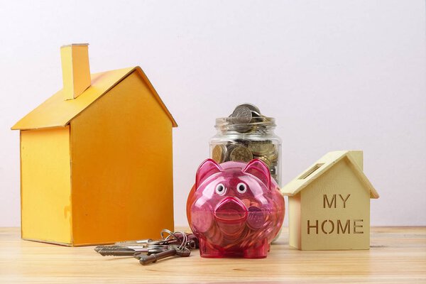 Piggy bank, small house and a bundle of house key. House saving concept