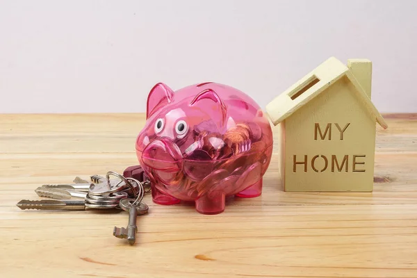 Piggy bank, small house and a bundle of house key. House saving concept