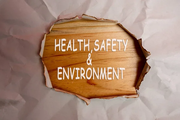 HEALTH, SAFETY AND ENVIRONMENT CONCEPT text at plain torn paper.