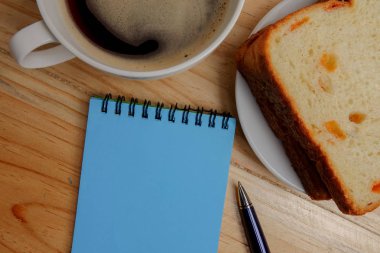 Boş not defteri ve kahve fincanı ofis tahtasının üzerinde.