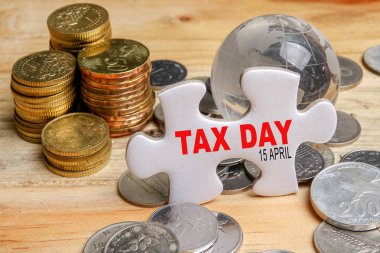 TAX DAY REMINDER CONCEPT. Stack of coins and puzzle with TAX DAY clipart