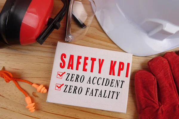 HEALTH AND SAFETY CONCEPT. Personal protective equipment on wooden table background with SAFETY KPI, ZERO ACCIDENT, ZERO FATALITY text.