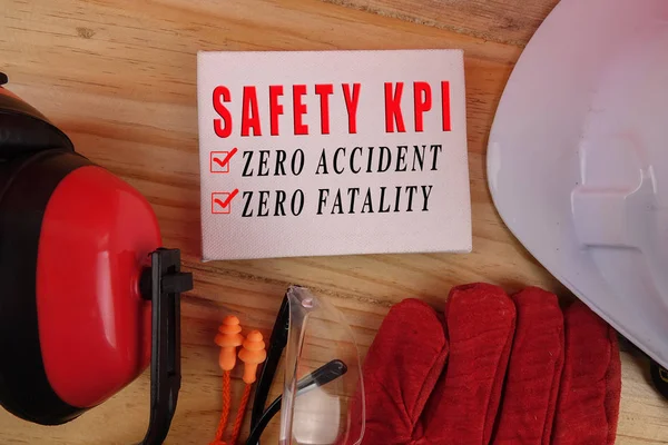 HEALTH AND SAFETY CONCEPT. Personal protective equipment on wooden table background with SAFETY KPI, ZERO ACCIDENT, ZERO FATALITY text.