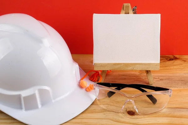 HEALTH AND SAFETY CONCEPT. Personal protective equipment on wooden table over red background.