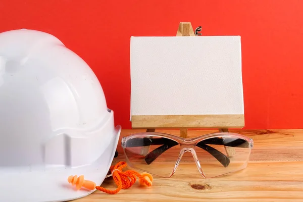 HEALTH AND SAFETY CONCEPT. Personal protective equipment on wooden table over red background.