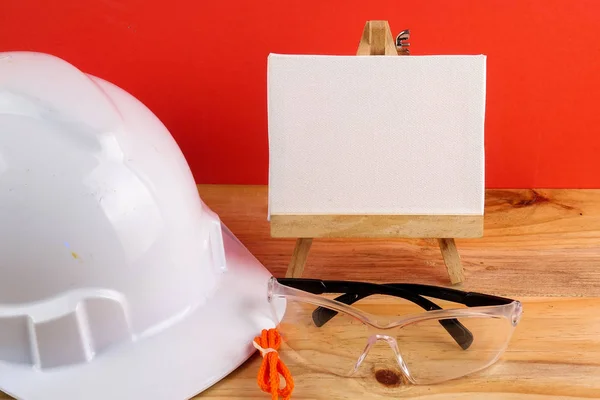 HEALTH AND SAFETY CONCEPT. Personal protective equipment on wooden table over red background.