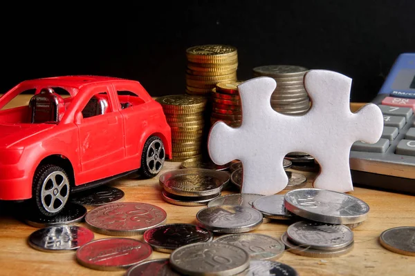 AUTO FINANCING CONCEPT : Small cars,coins,piece of puzzle and calculator on wooden table. Copy Space