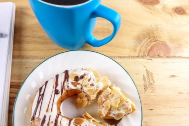 İş kavramı - üstten görünüm çörek, defter, kalem, kahve fincanı ve ahşap masa telefonu.