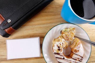 İş kavramı - üstten görünüm çörek, defter, kalem, kahve fincanı ve ahşap masa telefonu.