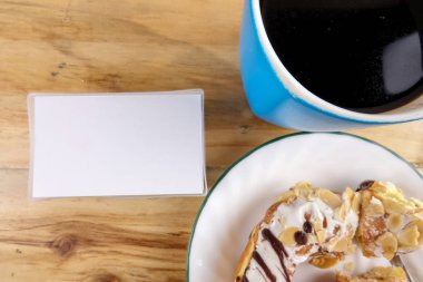 İş kavramı - üstten görünüm çörek, defter, kalem, kahve fincanı ve ahşap masa telefonu.