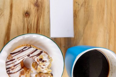 İş kavramı - üstten görünüm çörek, defter, kalem, kahve fincanı ve ahşap masa telefonu.