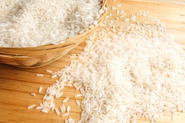 Hasır sepet ahşap bir masa üzerinde taze pirinç. Yan etkisi aydınlatma.