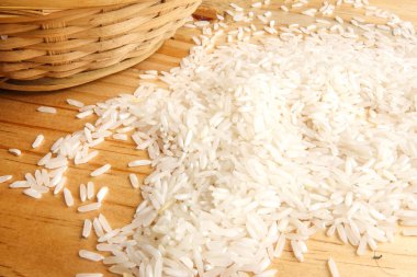 Hasır sepet ahşap bir masa üzerinde taze pirinç. Yan etkisi aydınlatma.