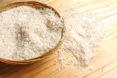 Hasır sepet ahşap bir masa üzerinde taze pirinç. Yan etkisi aydınlatma.