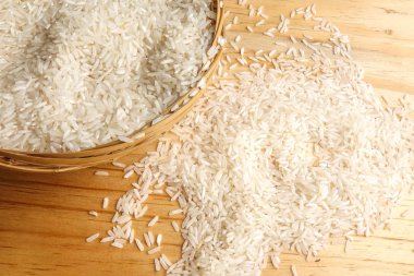 Hasır sepet ahşap bir masa üzerinde taze pirinç. Yan etkisi aydınlatma.