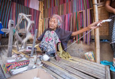 Lombok, Endonezya: 4 Haziran 2015 - Sasak yaşlı kadın geleneksel olarak iplik iğ tekerlek ile geleneksel Sasak köyünde, Desa Sasak Sade, Lombok Endonezya yapar.