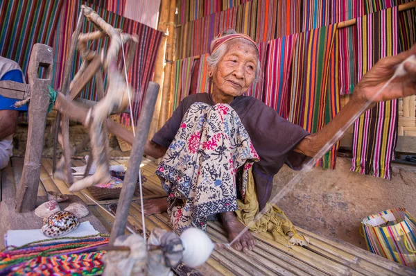 Lombok, Endonezya: 4 Haziran 2015 - Sasak yaşlı kadın geleneksel olarak iplik iğ tekerlek ile geleneksel Sasak köyünde, Desa Sasak Sade, Lombok Endonezya yapar.