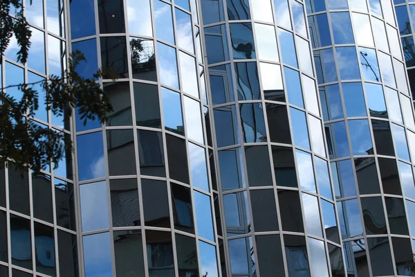 Şehrin gökyüzünün yansıması ve cam bir binanın duvarındaki kentsel manzara