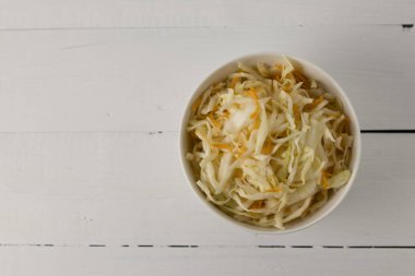 beyaz bir kasede beyaz bir lahanayla ahşap beyaz arka planda, üst manzara