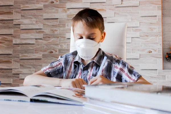 Evde koronavirüs salgınına karşı online dersler. Evde bir çocuk var ve ev ödevi yapıyor, karantina sırasında sosyal uzaklık, kendini soyutlama, online eğitim konsepti, tıp maskeli ev okulu öğrencisi.