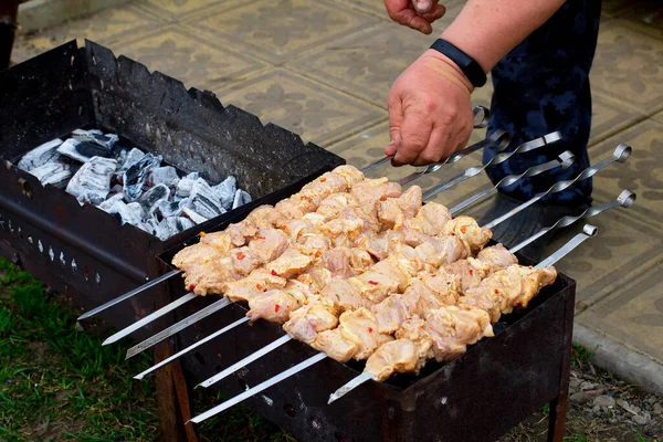 Adamın biri ızgarada çiğ domuz etiyle şiş çeviriyor. Taşralı adam barbekü yapıyor.
