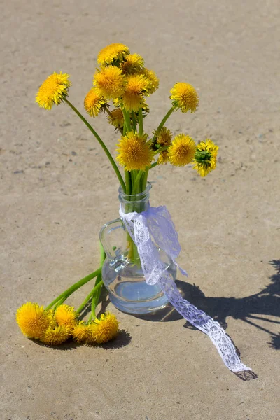 Baharda sarı karahindiba çiçekleri cam bir vazoda beton arka planda