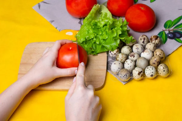 Kadın sağlıklı bir diyet salatası için domates kesiyor. Marul, domates, bıldırcın yumurtası. Kız sağlıklı yemek hazırlıyor.