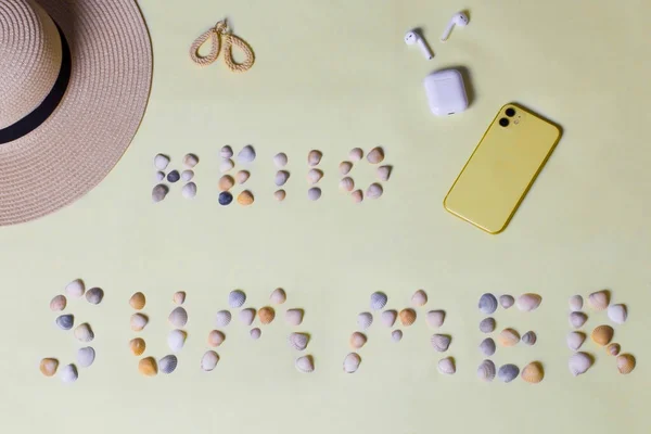 Sarı arka planda plaj aksesuarları. Güneş gözlüğü ve çizgili şapka. Yaz geliyor konsept