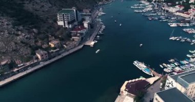 Güzel bir liman ve şehir altyapısı olan Kırım şehrinin üzerinde uçmak. Güzel beyaz yatlar ve tekneler deniz limanında duruyor. 4k drone.