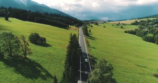 Scénický letecký pohled na silnici uprostřed louky na Vysokých Tatrách u vesnického deníku na Slovensku. Horská krajina a auto cestování ve Vysokých Tatrách
