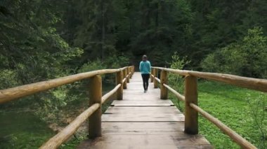 Resimli Yeşil Orman 'da Askıda Tek Başına Yürüyen Kadın Köprüsü. Çevresi Zengin Yeşil Ağaçlarla çevrili.