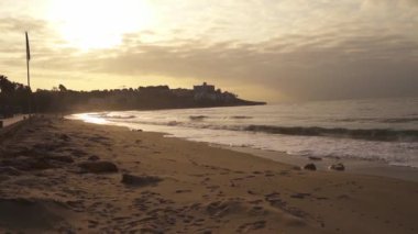Plano estabilizado del atardecer on una playa desierta del mediterraneo, junto con las olas del mar y la arena