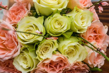 Genista 'nın zarif düğün buketi, kahverengi ahşap masanın üzerinde duran beyaz ve pembe güller.