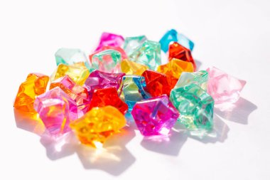 Beyaz zemin üzerinde güneşin parlaklığı olan parlak saydam cam taşlar. Yaratıcı arka plan, soyut doku, kopyalama alanı.