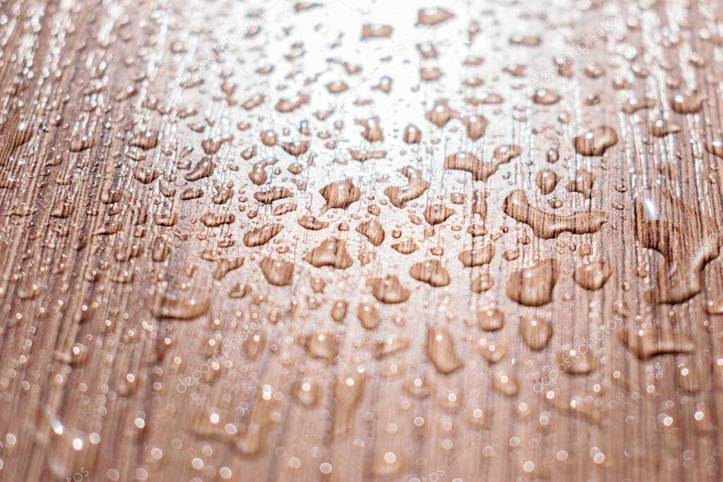 Water drops on a brown wooden table in the sun.Creative background,abstract texture.Selective focus,blurred background