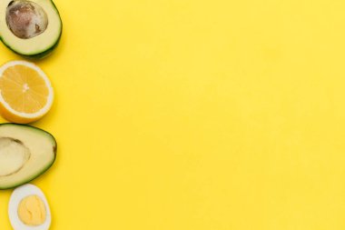 Düz ketojenik diyet. Avokado çerçevesi, sarı arka planda yumurta ve limon. Sağlıklı yiyecek kavramı.