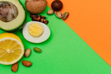 Düz ketojenik diyet. Vokado, yumurta, limon ve fındık yeşil ve turuncu arka planda. Sağlıklı gıda kavramı, üst görüş. Makyaj için alanı kopyala